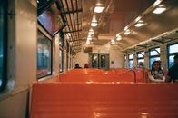 Interior of train wagon with metal shelves ad bright seats with passengers riding