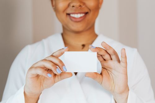 Free African American woman smiling, holding a blank card in hands, ready for branding or mockup. Stock Photo