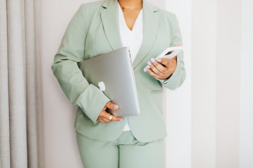 Free Person in Green Suit Holding Gadgets Stock Photo