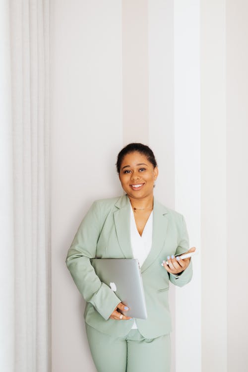 Woman in Green Suit Holding Gadgets