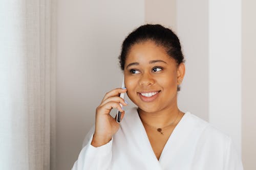 Free Smiling Woman in White Dress Shirt Holding Smartphone Stock Photo