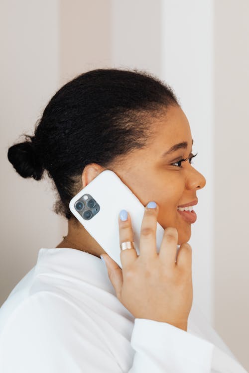 Free Woman in White Top Smiling while Talking on Cellphone Stock Photo
