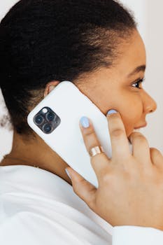 A woman engaged in a phone call, holding a smartphone close to her ear, expressing engagement.