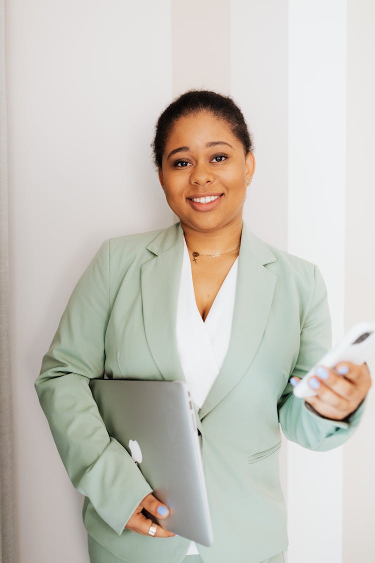 Smiling Woman In Light Green Suit Holding Gadgets