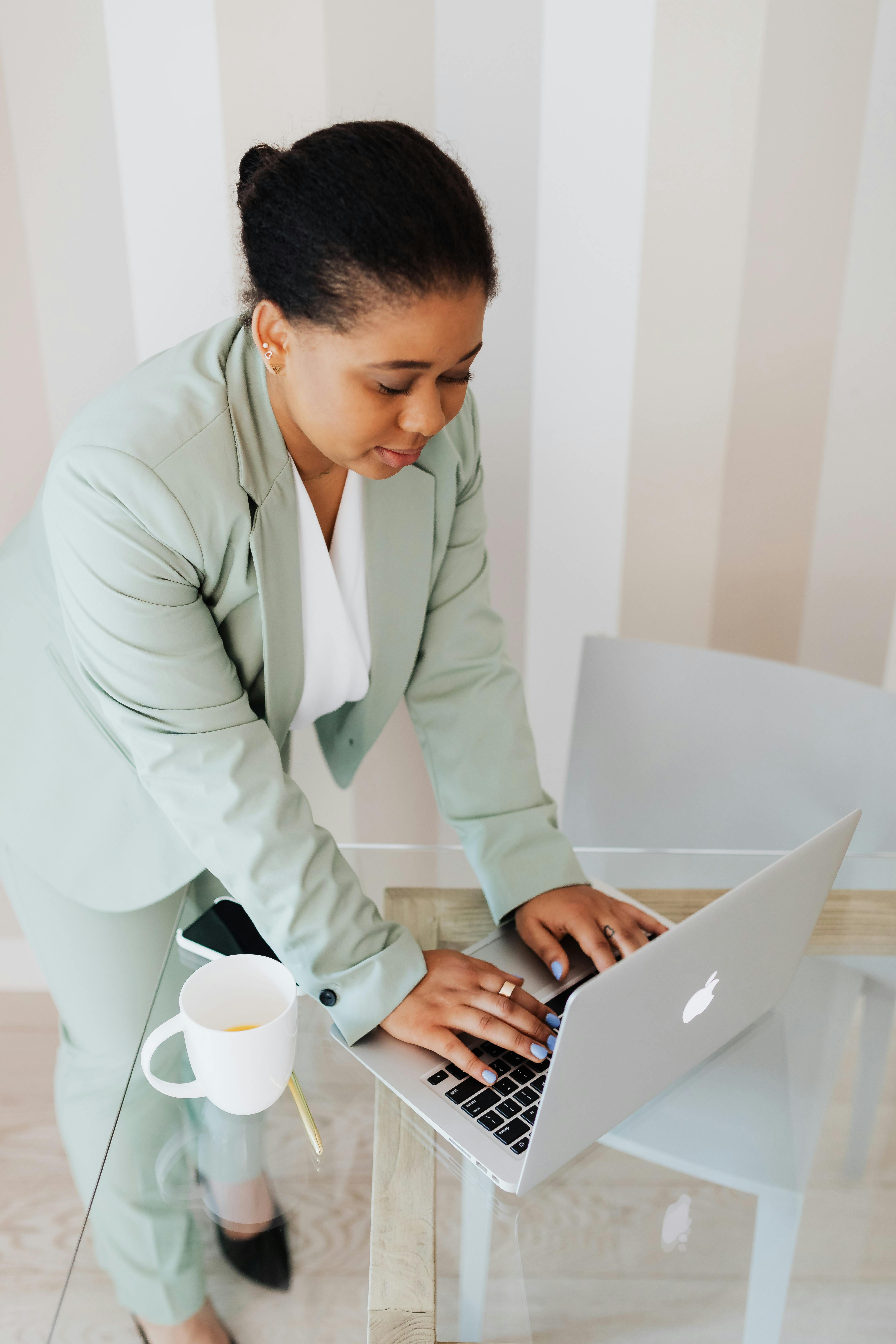 woman in light green suit typing on laptop