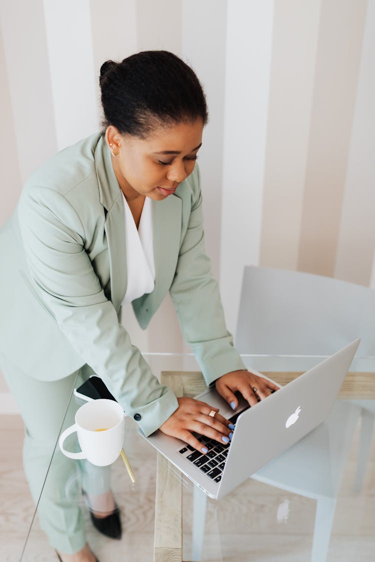 Woman In Light Green Suit Typing On Laptop