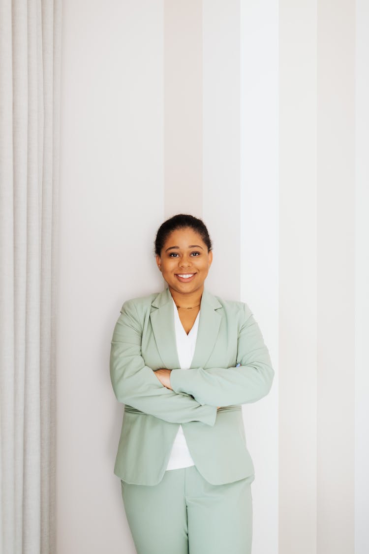 Woman In Light Green Suit Standing Near A Wall