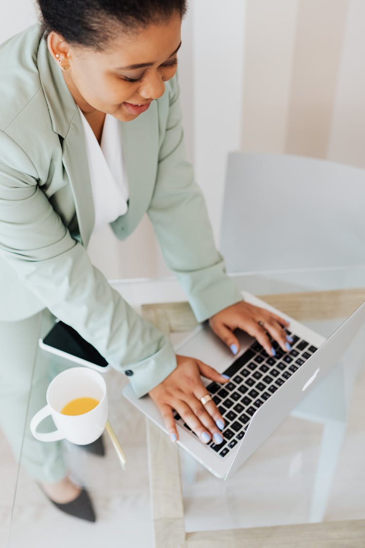 Woman In Light Green Suit Typing On Laptop