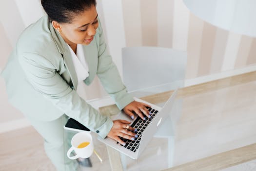 Businesswoman in a suit working on a laptop, illustrating modern professional life.