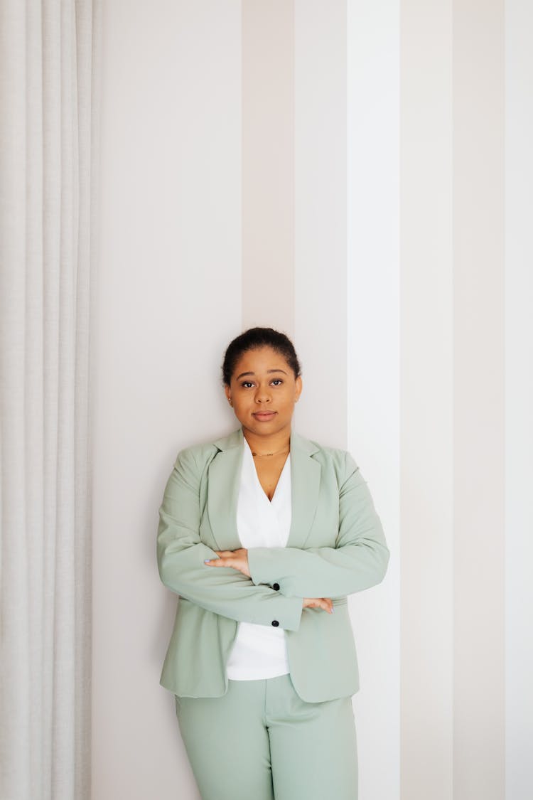 Woman In Light Green Suit Leaning On A Wall