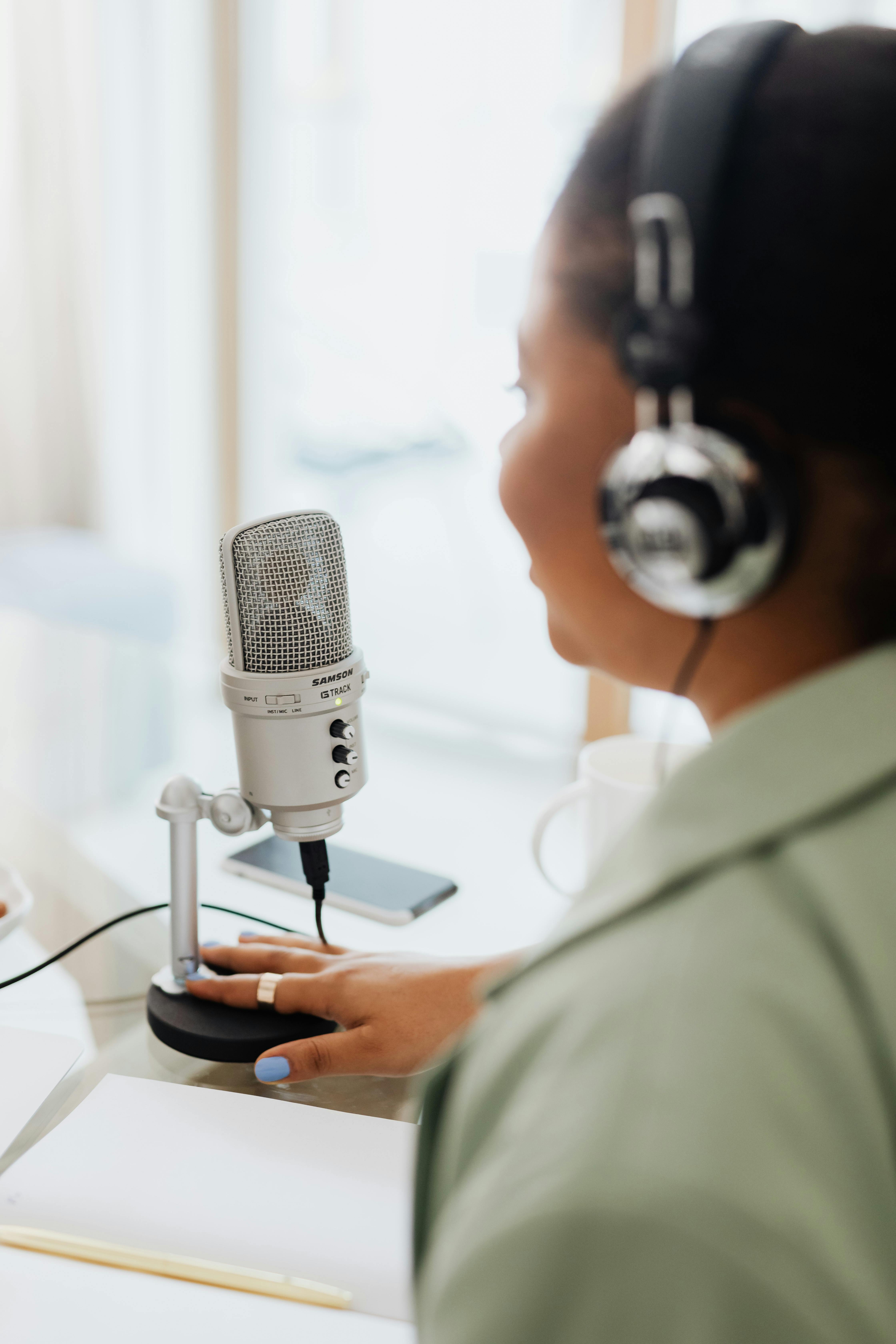 person wearing silver and black headphones holding microphone