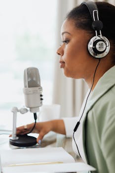 Side view of a woman recording a podcast with a condenser microphone and headphones.