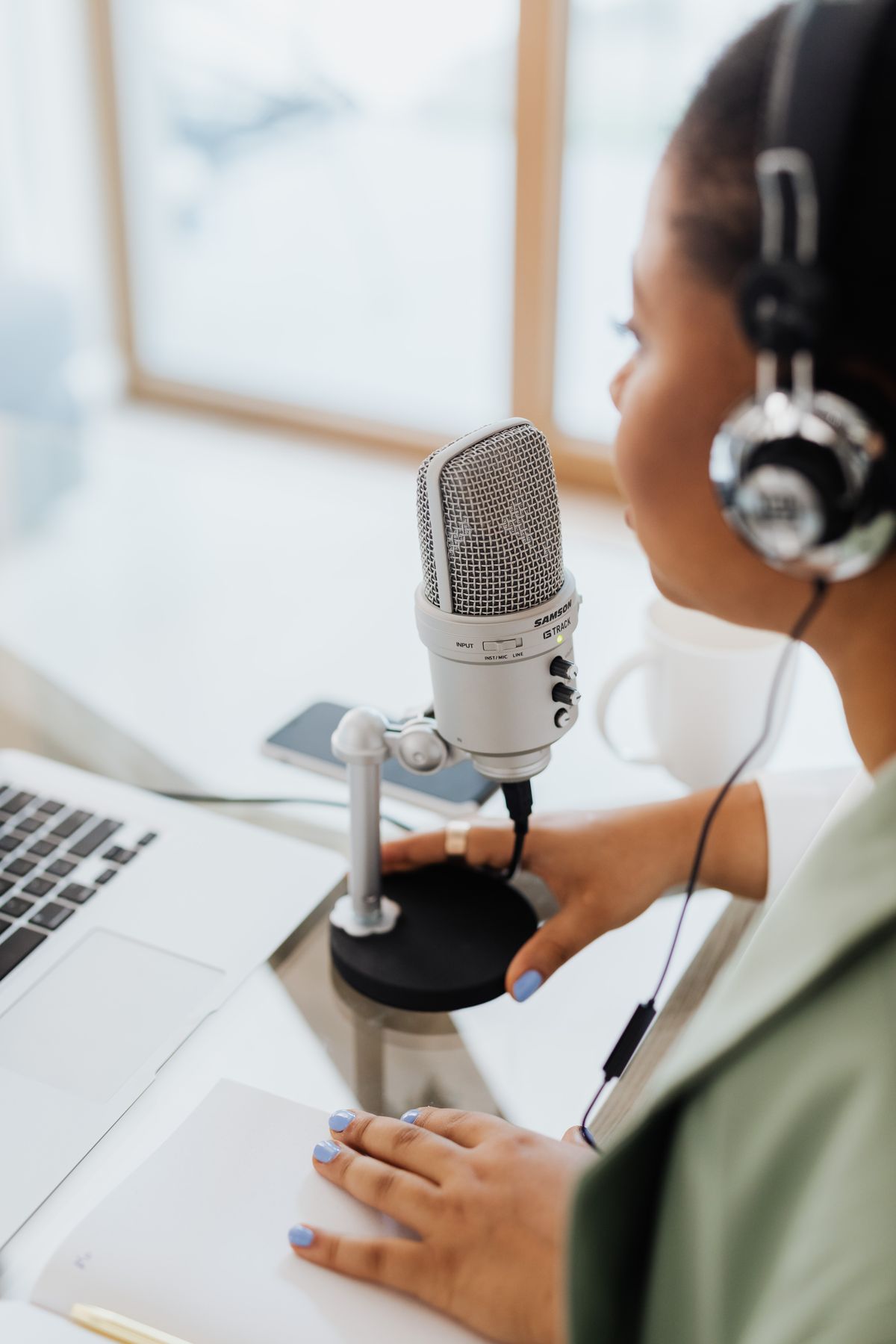 Artist singing into a studio microphone wearing headphones in the booth