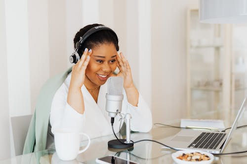 Woman Wearing Headphones Looking at Laptop and Smiling