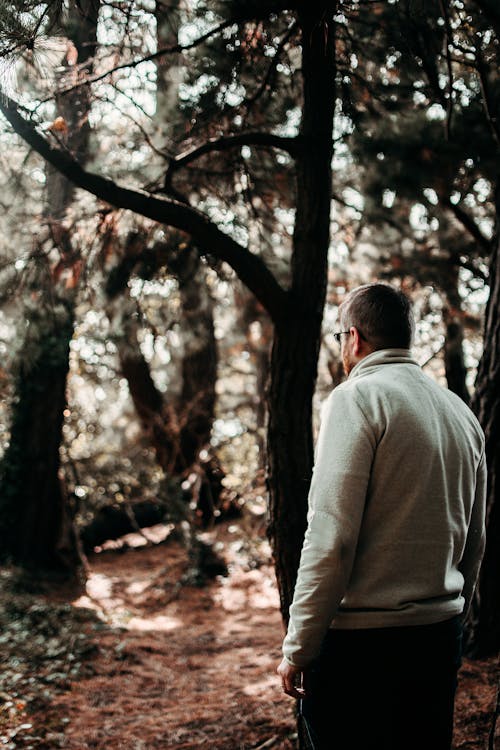 Man in Gray Jacket Standing in Front of Trees