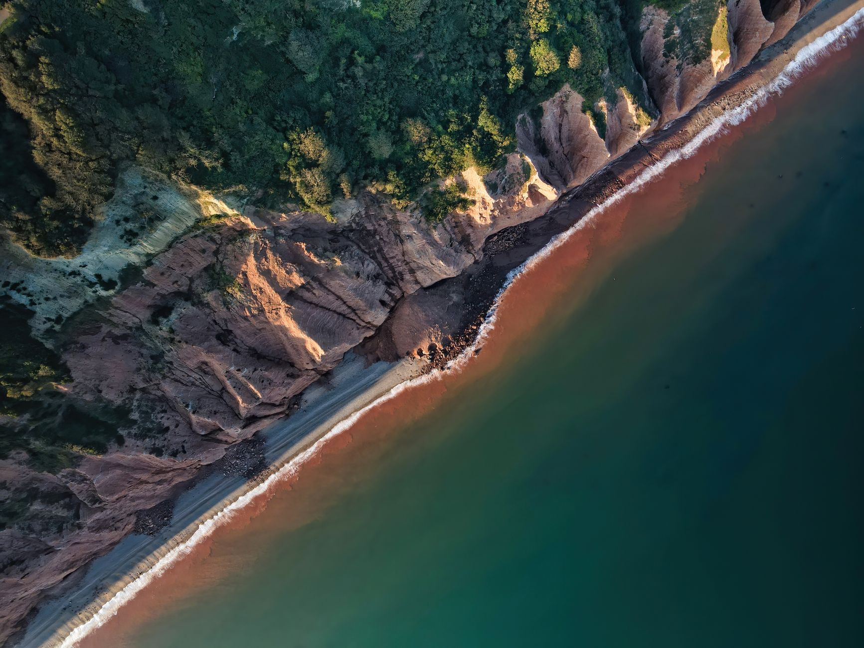 Breathtaking aerial shot of Sidmouth's Jurassic coastline, showcasing vibrant cliffs and serene ocean waters.