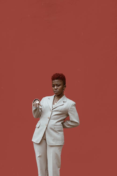 Woman in White Suit Standing Beside Red Wall