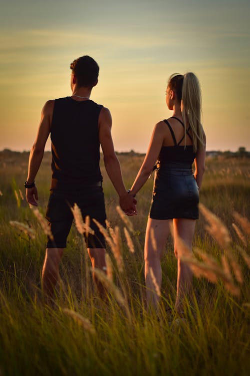 Couple Holding Hands Standing on Green Grass Field