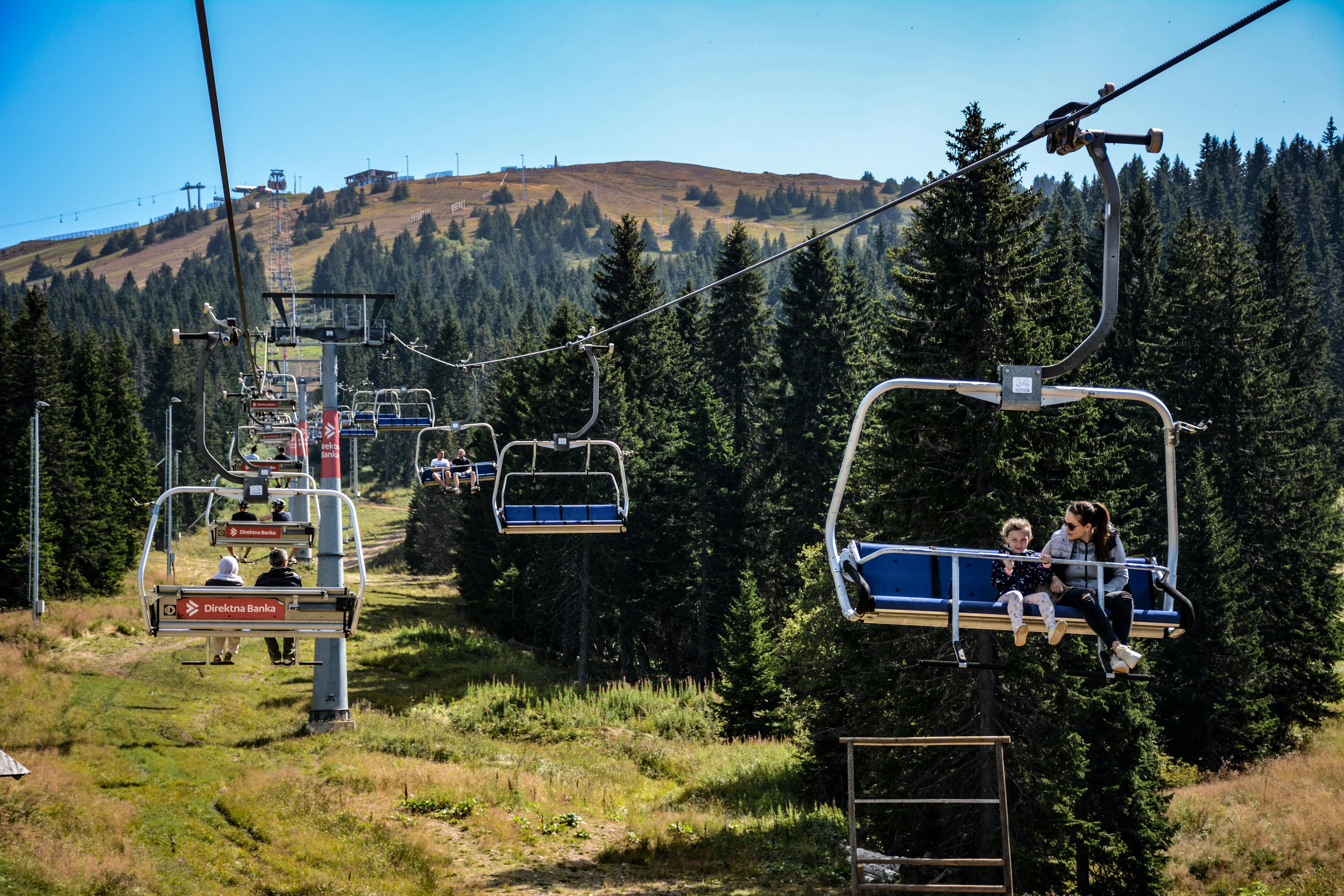 Enjoying a serene ski lift ride through lush forested mountains on a sunny day.