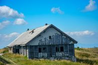 Gray Wooden House on Green Grass Field Under Blue Sky