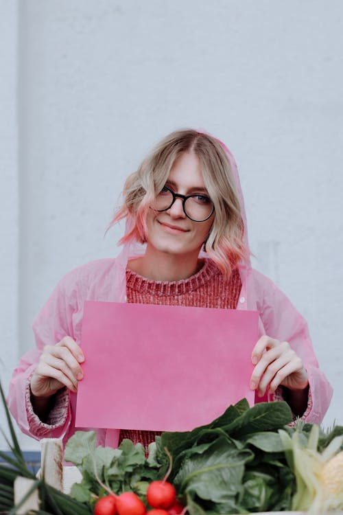 A Woman in Raincoat Holding a Pink Paper