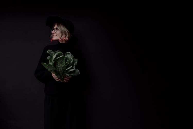 Woman In Black Dress Holding Green Leaves 