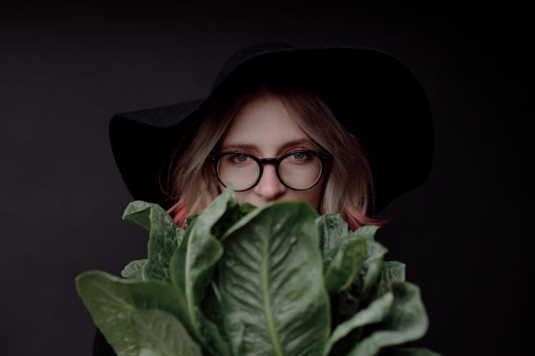 Woman In Black Hat And Eyeglasses Holding Green Vegetables 