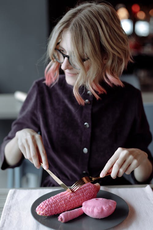 Woman With Blonde Hair Slicing Pink Corn 