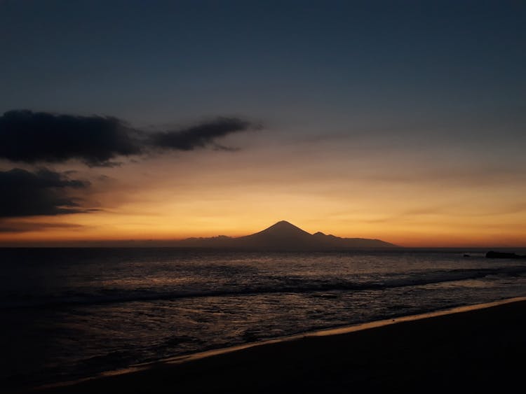 Sea And Silhouette Of Volcano At Sunset