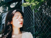 Woman in White Shirt Standing Beside Green Leaf Plant