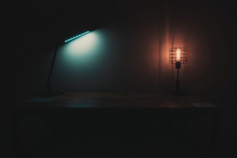 Different lamps with cold and warm lights placed on table in dark room