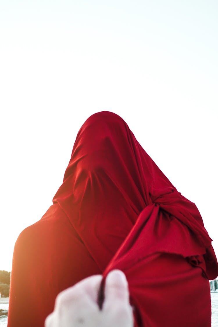 Person Pulling Red Cloth Covering Unrecognizable Person