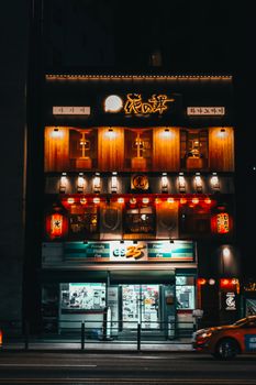 城市店面在夜间灯火通明，标牌和霓虹灯交相辉映，营造出充满活力的生动氛围