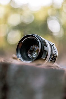 A detailed close-up of a camera lens on a surface outdoors with a blurred bokeh background.