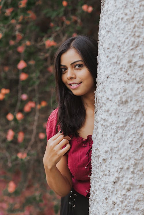 Woman in Red Shirt Leaning on White Wall