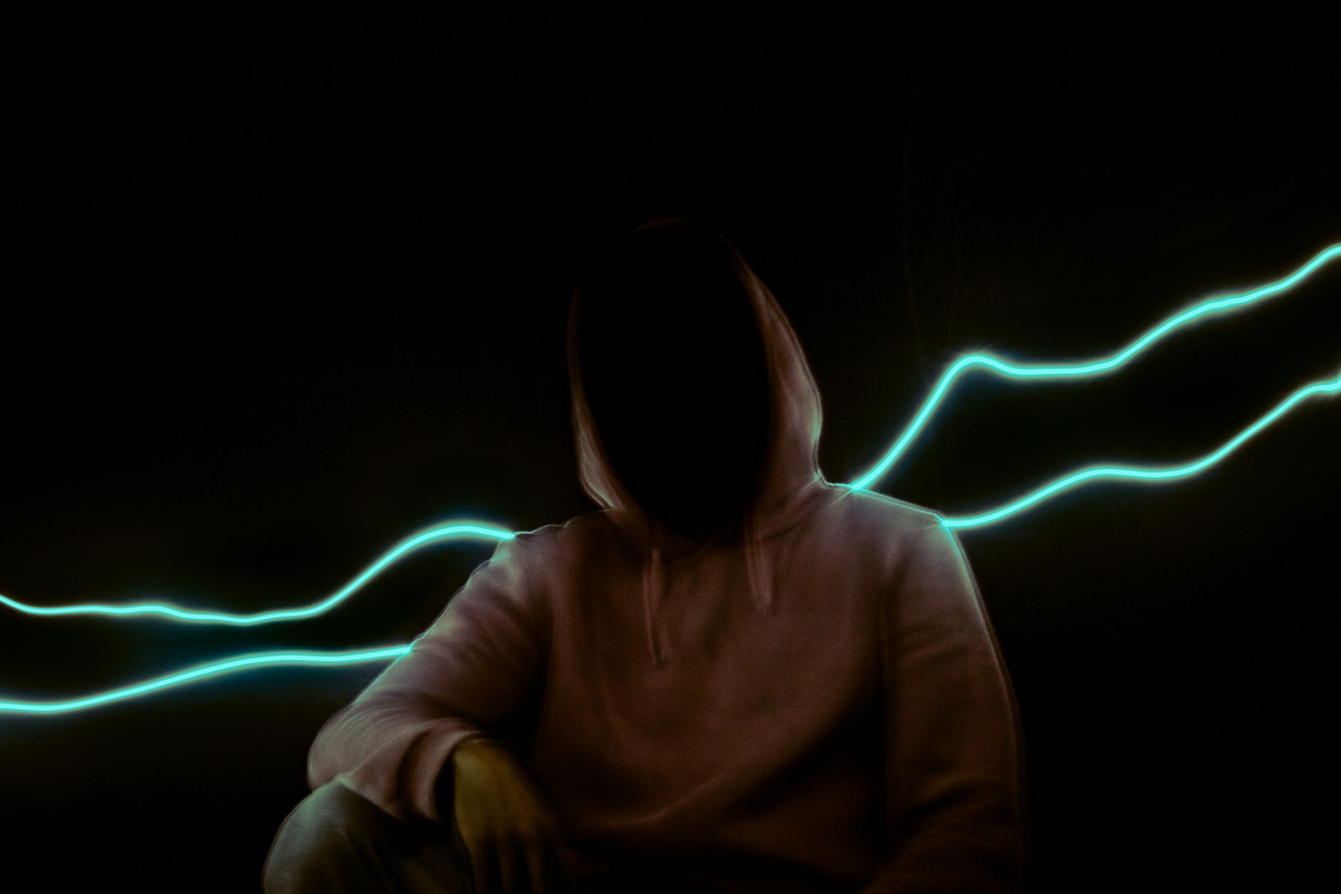 شخص لا يظهر وجهه تحت غطاء رأس، تحيط به خطوط ضوئية زرقاء على خلفية سوداء