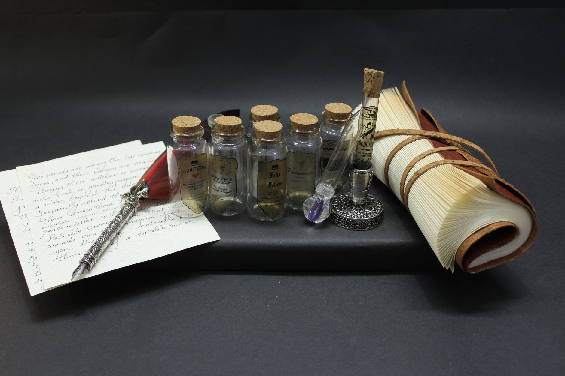 Vintage still life featuring glass ink bottles, quill pen, and leather-bound notebook.