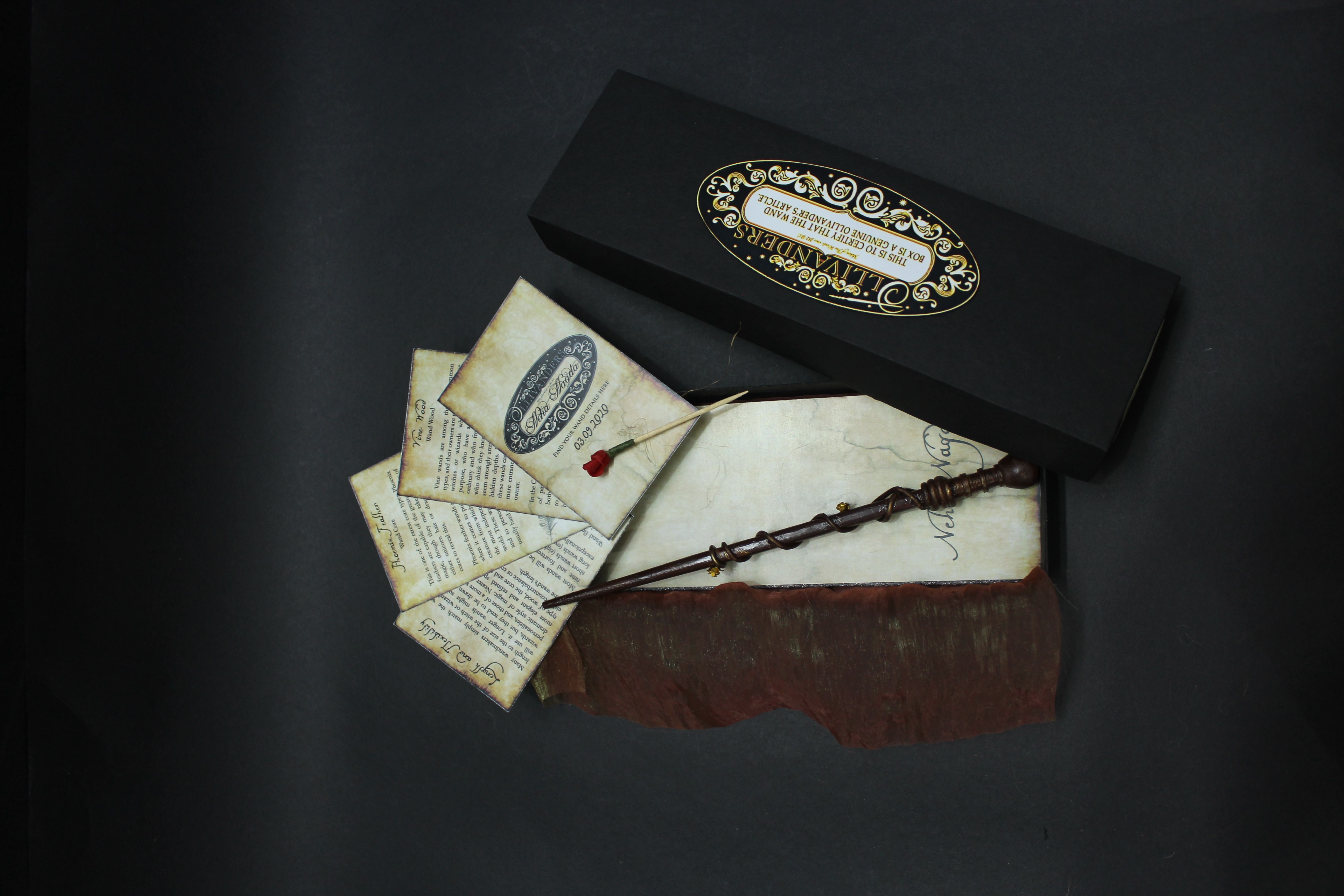 Magical wand with vintage letters and Ollivanders packaging on black background.