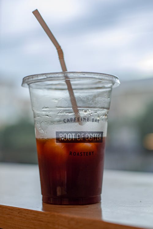 Plastic cup with iced tea on wooden table