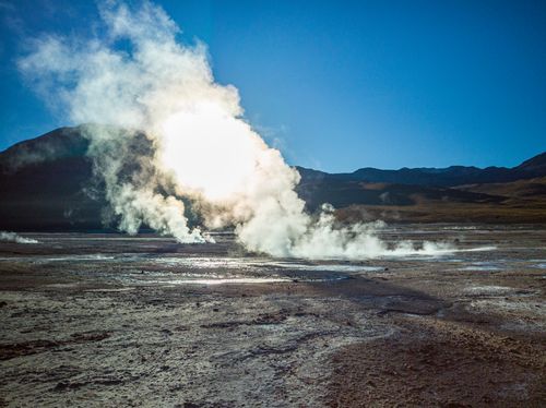 Free Vibrant geyser eruption creating steam in the Chilean desert landscape with clear blue skies. Stock Photo