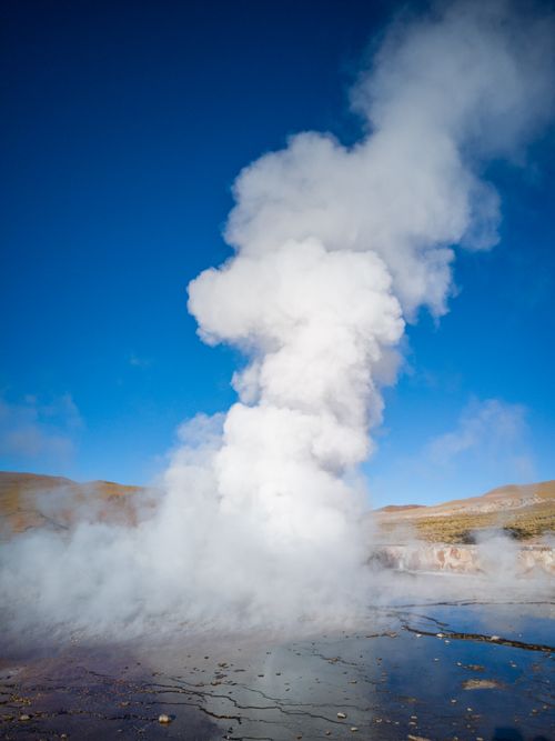 Free Steaming geyser eruption in the barren landscape of Antofagasta, Chile, under a clear blue sky. Stock Photo