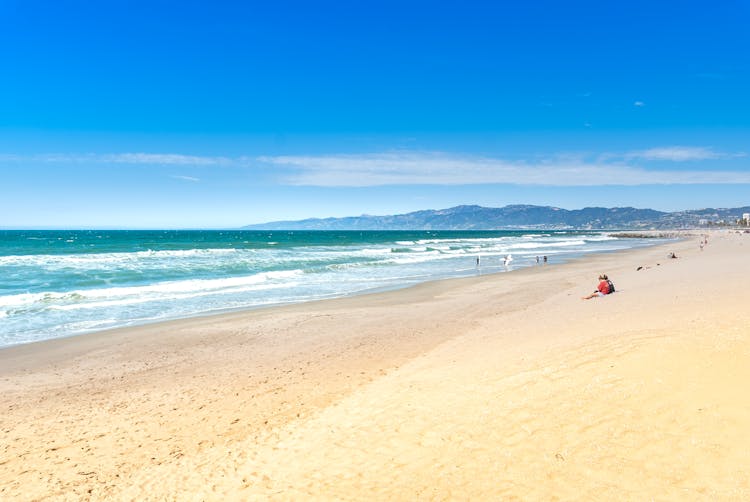 People Relaxing At Sandy Beach