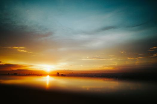 A stunning sunset with vivid colors over a calm ocean reflects a serene sky.