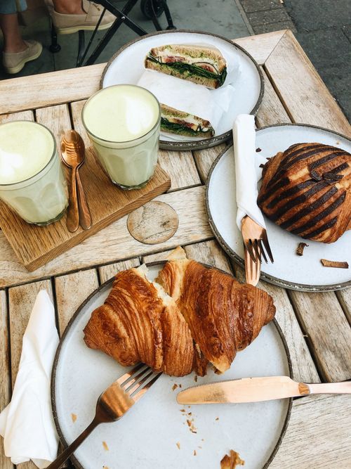 Free Experience a sophisticated brunch in London with croissants, sandwiches, and matcha lattes on a rustic wooden table. Stock Photo