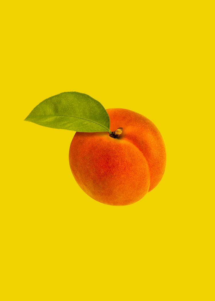 Studio Shot Of Ripe Peach On Yellow Background 