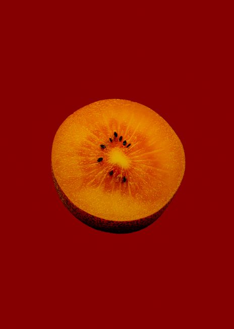 Vibrant close-up of a juicy tropical fruit slice with seeds on a red background.