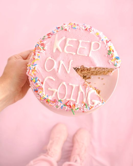 A pink cake with sprinkles and 'KEEP ON GOING' message inspires positivity.