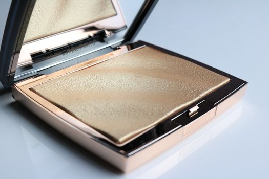 Elegant open compact with shimmering gold powder in a chic, reflective design.