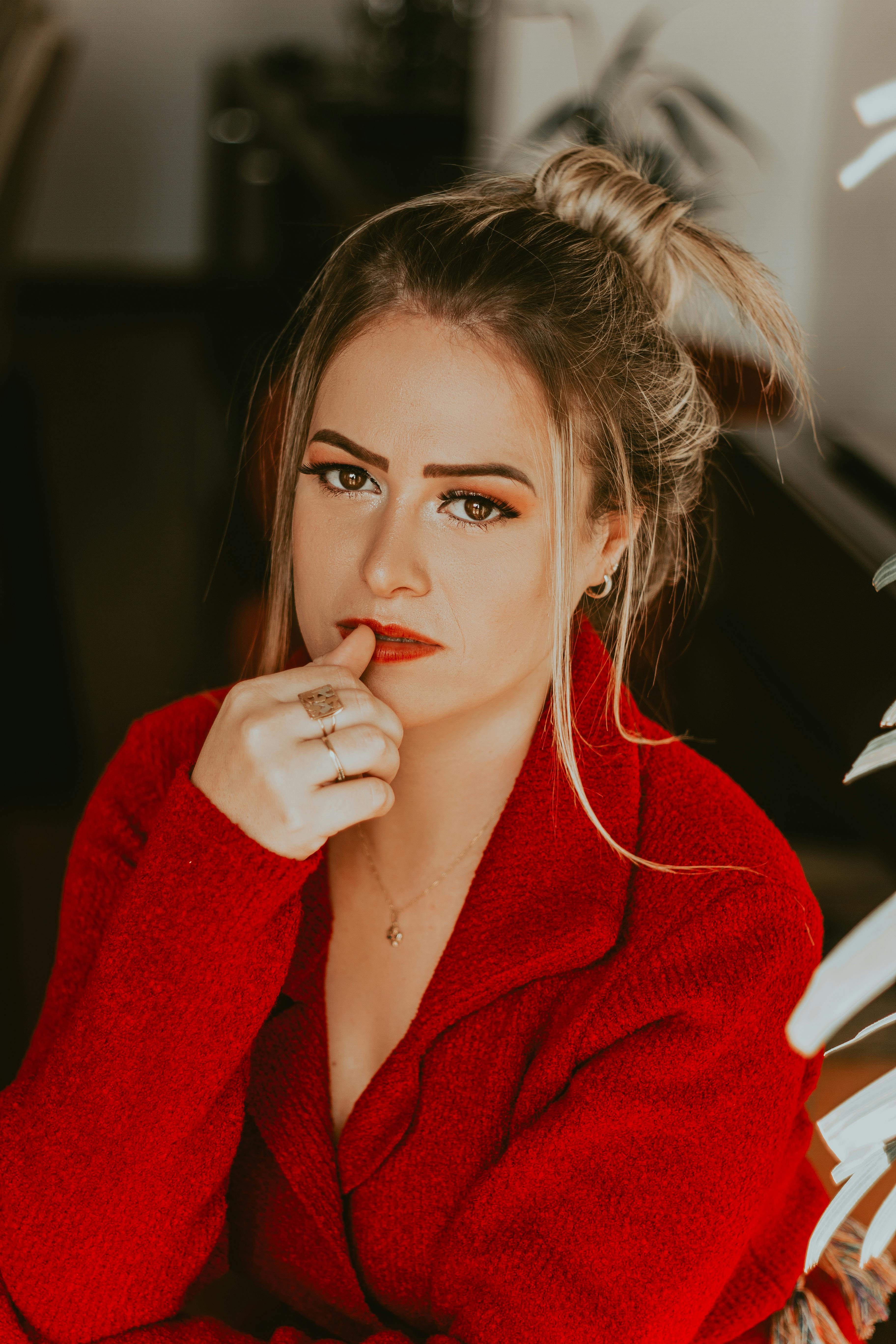 Young attractive female with makeup in red velvet jacket thoughtfully looking at camera