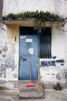 成都一扇质朴的蓝色大门上，扫帚倚靠，油漆剥落，透着复古的气息